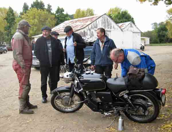 While Fred pours oil in the bike, others give George advice